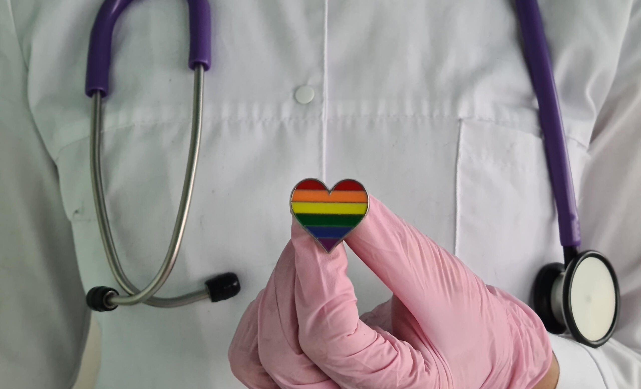 Woman doctor with lgbt heart flag in hand in clinic