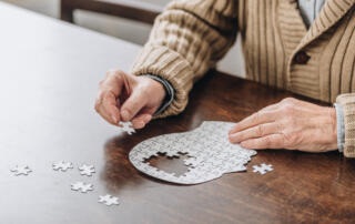elderly man completing a puzzle in the shape of a head