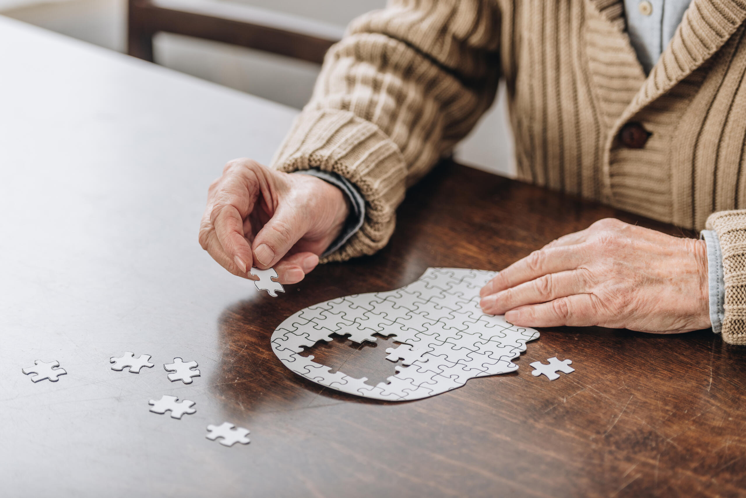elderly man completing a puzzle in the shape of a head