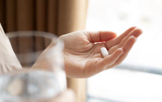 Woman hand holding antibiotic pill and glass of water